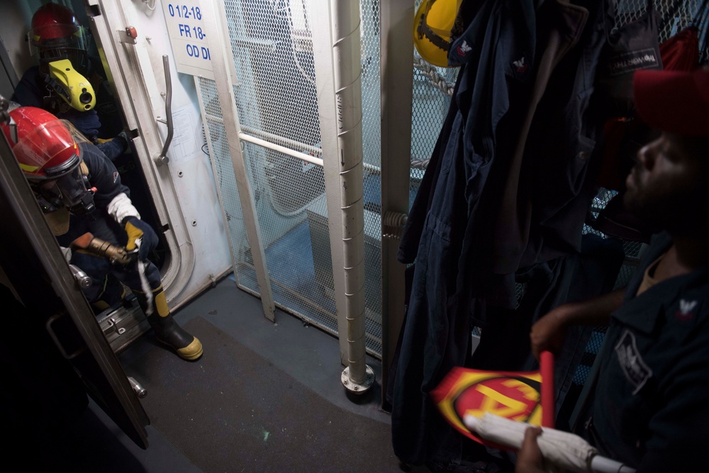 U.S. Sailors engage a simulated fire during a general quarters drill aboard the guided-missile destroyer USS Spruance