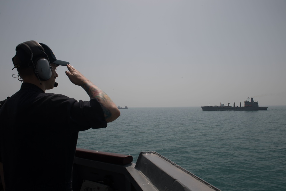 U.S. Navy Quartermaster salutes the fleet replenishment oiler USNS Kanawha