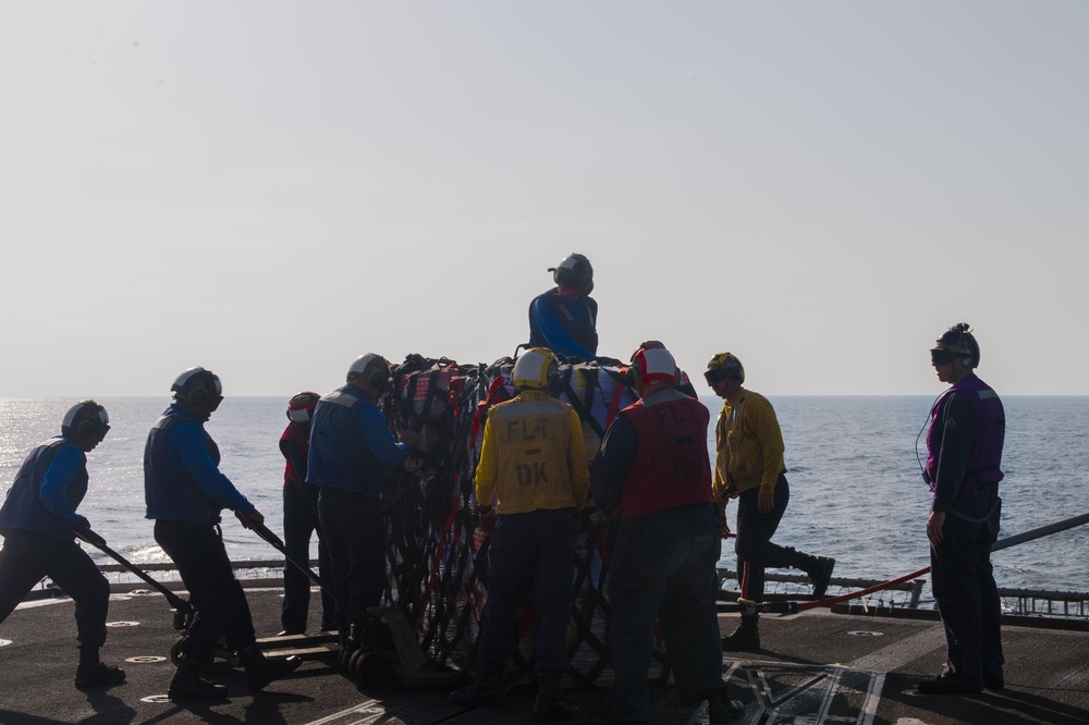 U.S. Sailors move pallets off the flight deck during a replenishment-at-sea