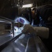 U.S. Navy Hull Maintenance Technician welds a coffee machine to a table aboard the guided-missile destroyer USS Stockdale