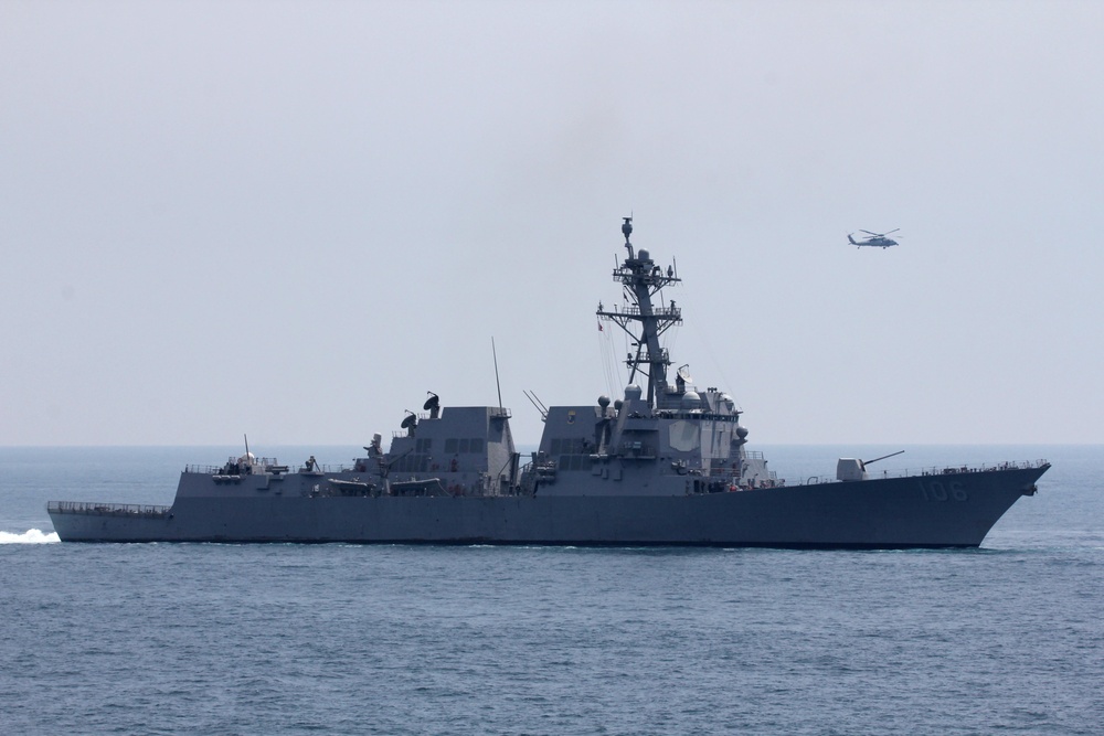 An MH-60S helicopter flies near USS Stockdale