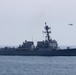 An MH-60S helicopter flies near USS Stockdale