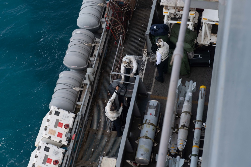 U.S. Sailors load cargo onto the flight deck