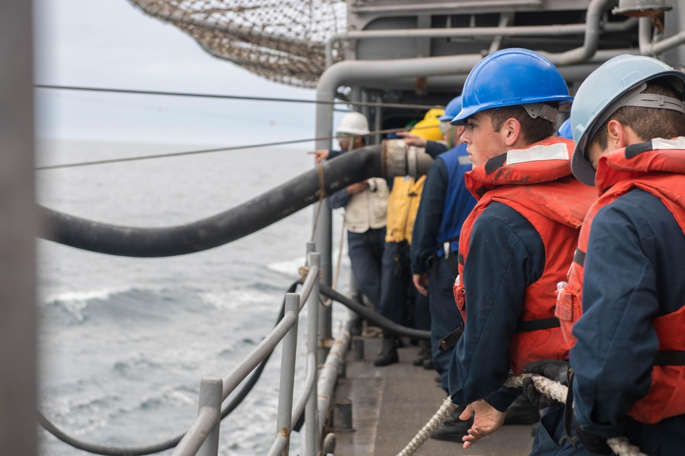 U.S. Navy Electronics Technician handles the fuel line aboard the guided-missile cruiser USS Mobile Bay