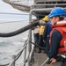 U.S. Navy Electronics Technician handles the fuel line aboard the guided-missile cruiser USS Mobile Bay