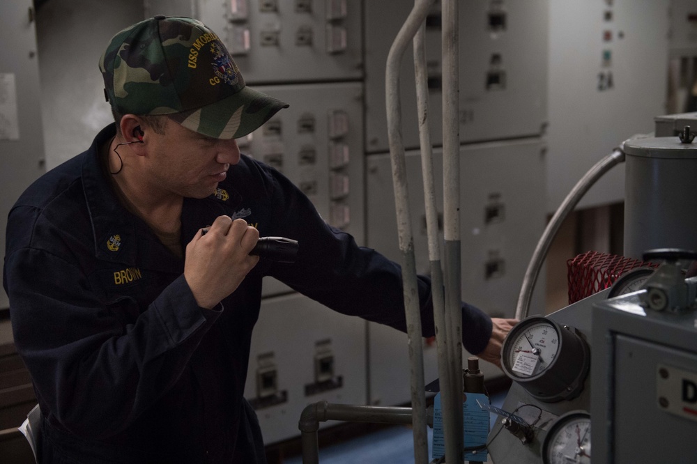 U.S. Navy Chief Machinist Mate inspects a low pressure air compressor aboard USS Mobile Bay