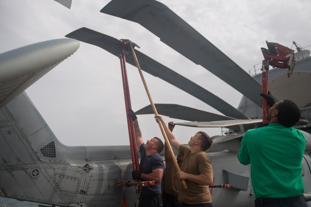 U.S Sailors install support crutches for the rotor wings of an MH-60R Sea Hawk