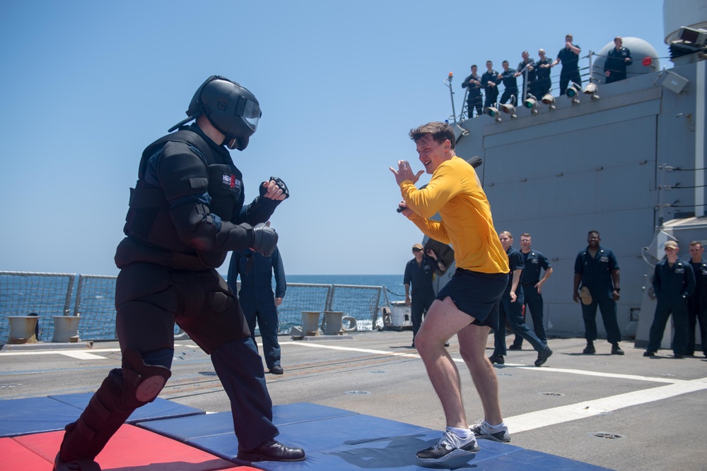 U.S. Navy Ensign attempts to subdue an opponent after being sprayed with oleoresin capsicum spray during security reaction force basic training aboard USS Stockdale