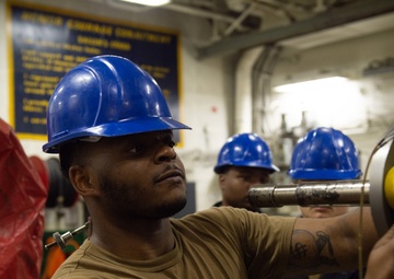 U.S. Sailor conducts maintenance on a jet engine
