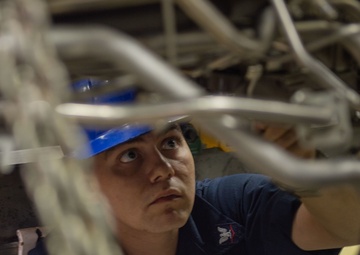 U.S. Sailor conducts maintenance on a jet engine