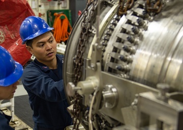 U.S. Sailors conducts maintenance on a jet engine