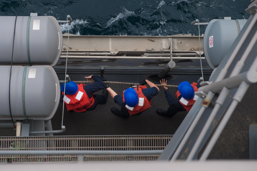 U.S. Sailors pull in a line as USS Mobile Bay conducts a replenishment-at-sea with USNS Alan Shepard in the Arabian Gulf