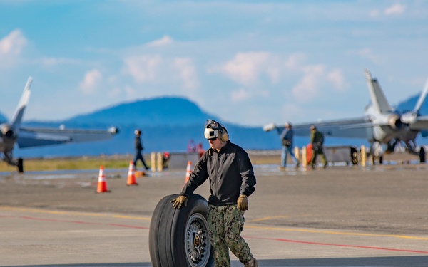 An aircraft maintainer from VR-61 rolls a DC-9 landing wheel into a hangar at Ault Field.