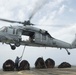 U.S. Sailors connects cargo to an MH-60S Sea Hawk on the flight deck of USS Spruance