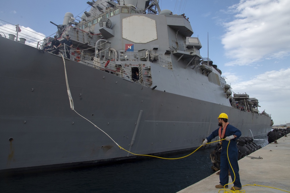 A Naval Support Activity (NSA) Souda Bay port operations line handler heaves a mooring line as the Arleigh Burke-class guided-missile destroyer USS Ross (DDG 71) moors pierside at Souda Bay, Greece, April 12, 2019.