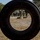 Balikatan 2019: Marines with 3/6 Interact with Philippine Marines The image is shot through the hole of a large tire in the foreground, framing a military physical training exercise on a dry, dusty field. Multiple personnel in military-style green uniforms and camouflage pants are engaged in tire-flipping and running drills. A group of observers stands in the background watching the activity.
