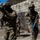 Balikatan 2019: 3/6 room clearing drill, multi-National Training with the AFP The image shows military personnel in MARPAT (Marine pattern) camouflage uniforms conducting urban combat training exercises. They are equipped with training weapons featuring blue barrel attachments, indicating simunition or force-on-force training ammunition. The exercise appears to take place in a mock urban environment with concrete block walls.