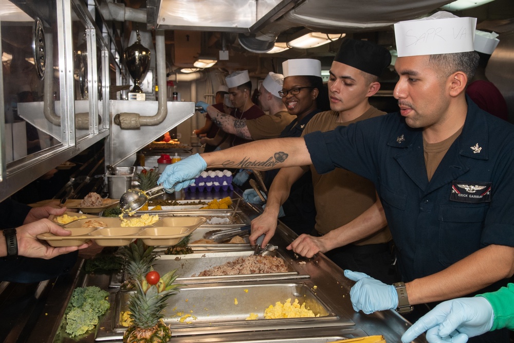 U.S. Sailors serve food in the galley