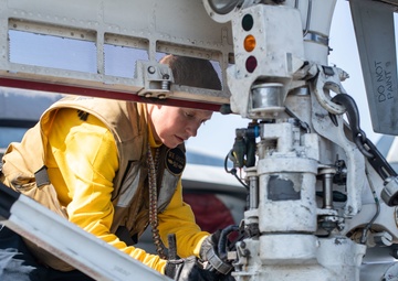 U.S. Sailor secures a chain to an F/A-18E Super Hornet