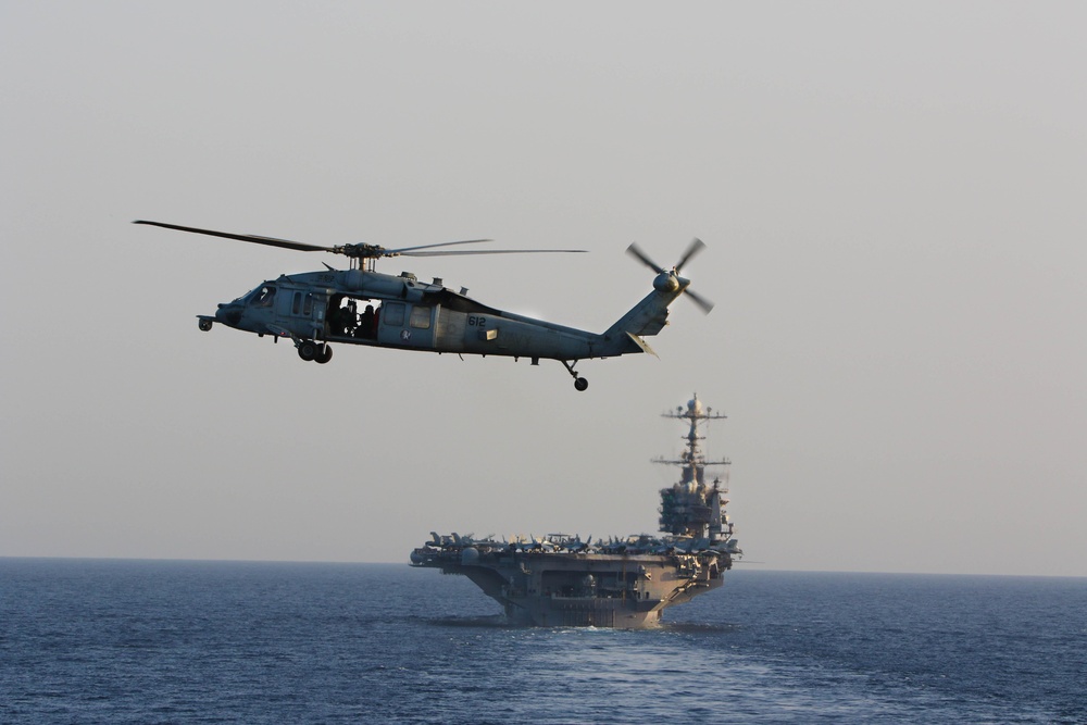 An MH-60S Sea Hawk hovers in front of USS John C. Stennis in the Red Sea