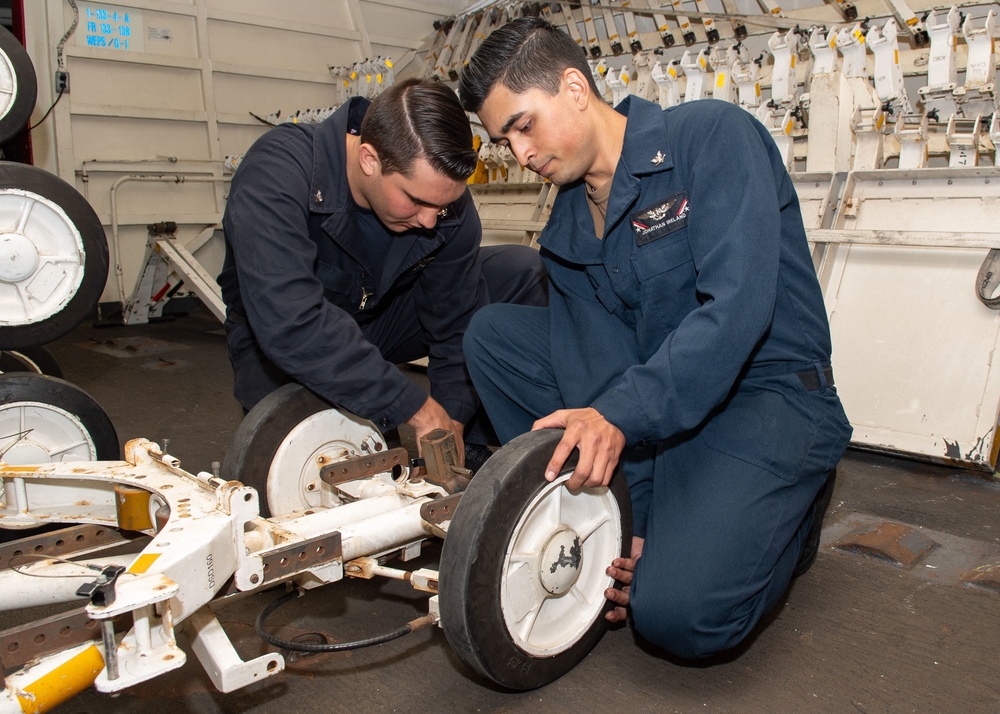 U.S. Sailors adjust brakes on a weapons transporter