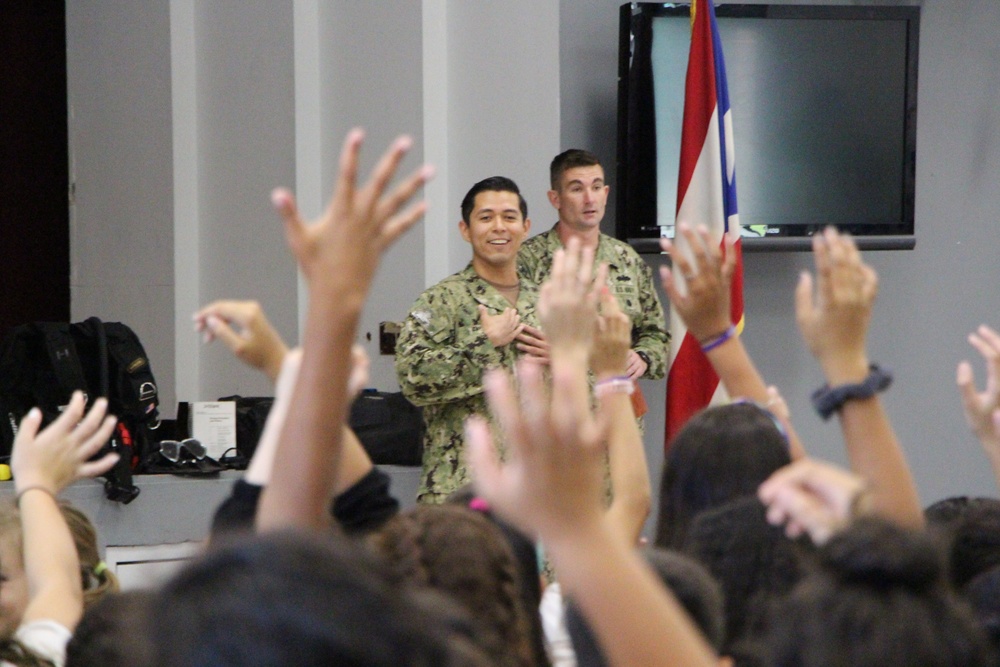 Builder 2nd Class Zavier Favilla from Explosive Ordnance Group 2 engages with students from Antilles Middle School on Fort Buchanan as a part of Navy Week Puerto Rico.