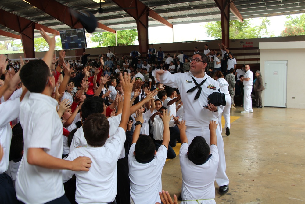 Electronics Technician Nuclear 1st Class Jonathan Velasquezrivera from the USS San Juan (SSN 571) hands out hats to students at the American Military Academy in Bayamón as a part of Navy Week Puerto Rico.