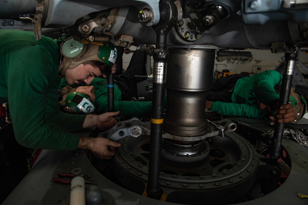 U.S. Sailors conduct maintenance on the scissors assembly of an MH-60S Sea Hawk