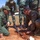 Humanitarian Mine Action increases demining capacity in Morocco Military personnel in different uniforms are gathered outdoors around a ground-level demonstration or training exercise. A soldier in US Marine Corps MARPAT camouflage and a soldier in olive green uniform are kneeling over a device partially buried in dirt, with wires and components visible. Several other uniformed personnel stand observing in the background, suggesting a joint training or instructional scenario.