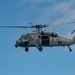 An MH-60S Sea Hawk flies alongside the aircraft carrier USS John C. Stennis (CVN 74)