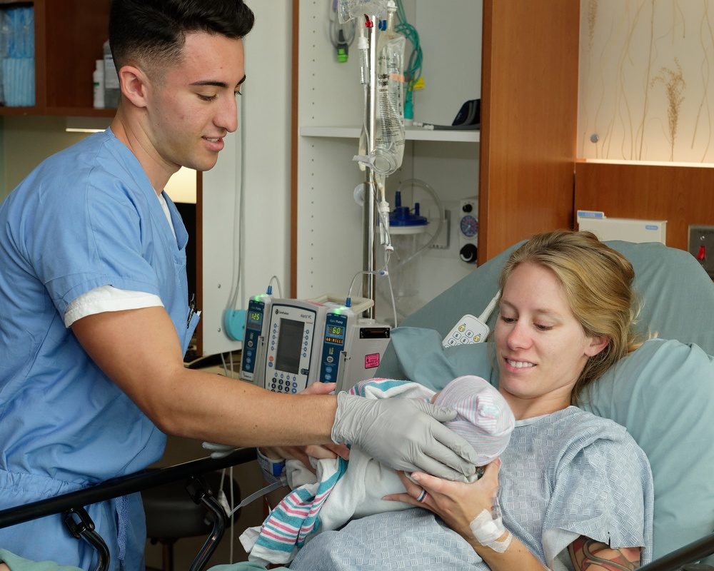 Hospital Corpsman Hands Newborn to Mother