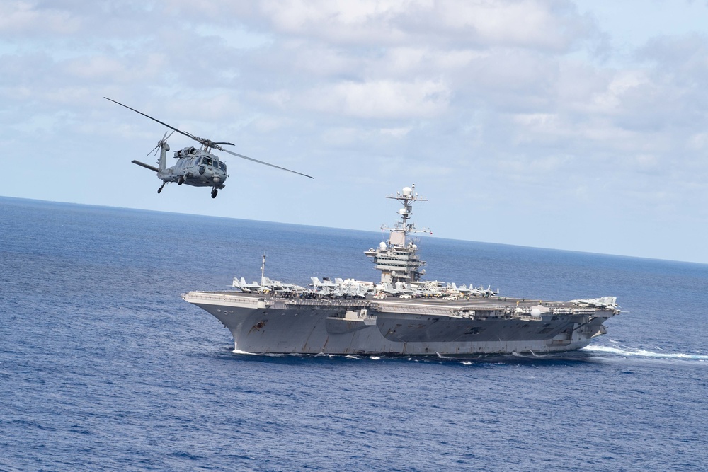 An MH-60S Sea Hawk, assigned to Helicopter Sea Combat Squadron (HSC) 14, flies alongside the aircraft carrier USS John C. Stennis (CVN 74