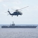 An MH-60S Sea Hawk, assigned to Helicopter Sea Combat Squadron (HSC) 14, flies alongside the aircraft carrier USS John C. Stennis (CVN 74)
