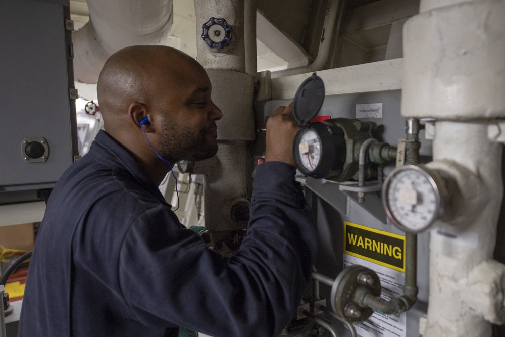 Machinist's Mate Fireman Jose Colon checks gauges inside the main engine room aboard the Arleigh Burke-class guided-missile destroyer USS Momsen (DDG 92).