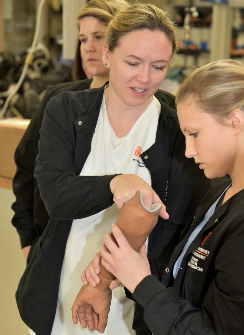 Nurses from AUM inspect a realistic prosthetic arm while at Walter Reed Bethesda