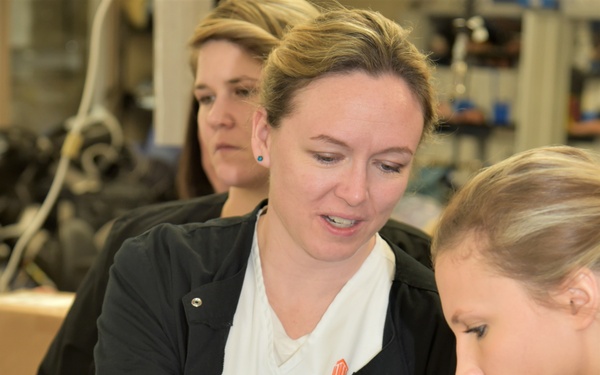 Nurses from AUM inspect a realistic prosthetic arm while at Walter Reed Bethesda