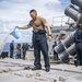 Gunner’s Mate 2nd Class Darrytt James Asuncion splashes a bucket of soap and water onto the verticle missile launch system during a fresh water wash down aboard the Arleigh Burke-class guided-missile destroyer USS Curtis Wilbur (DDG 54).