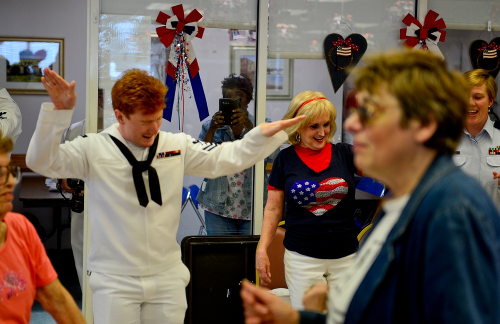 Gunner’s Mate 2nd Class Christian Rosas, attached to USS Milwaukee (LCS 5), dances with members of the Arrochar Friendship Club