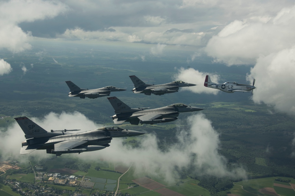 Scat VII, Robin Olds' P-51 Mustang, flies along Spangdahlem F-16C aircraft