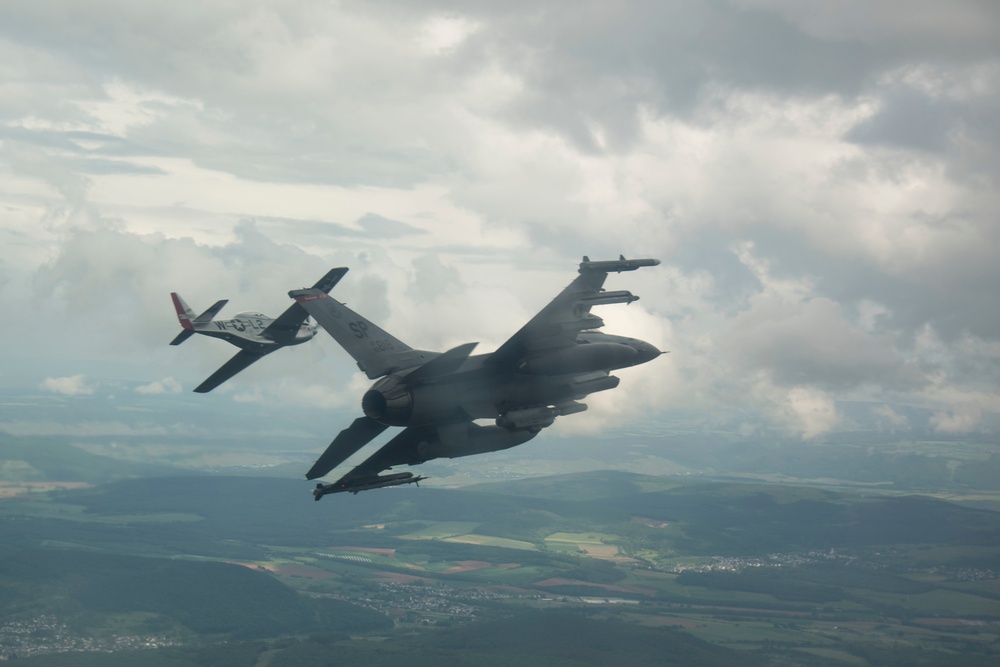 Scat VII, Robin Olds' P-51 Mustang, flies along Spangdahlem F-16C aircraft