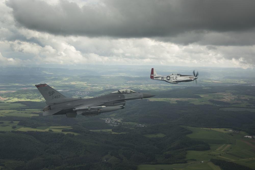 Scat VII, Robin Olds' P-51 Mustang, flies along Spangdahlem F-16C aircraft