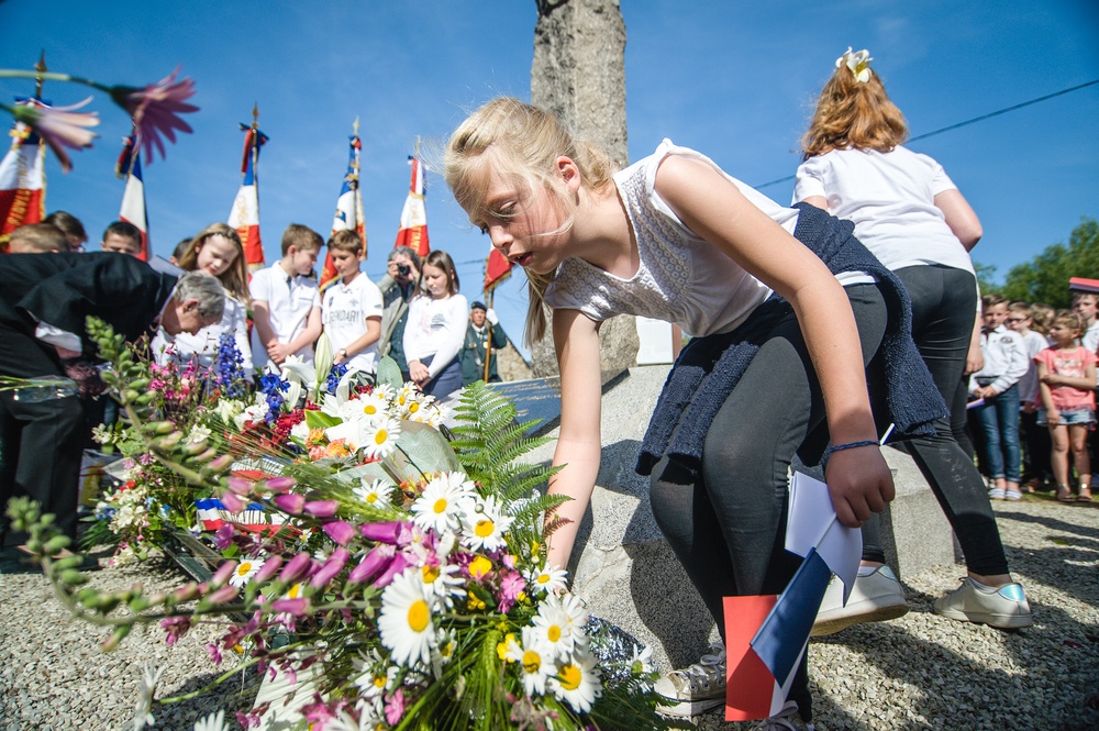 Children lay flowers at base of memorial