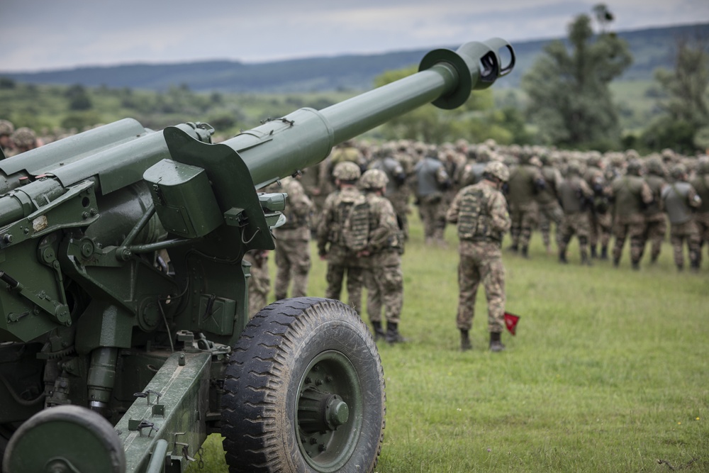 Soldiers from Romania and the U.S. stand in a combined formation in front of a static display of Romanian Land Force vehicles and artillery weapons during the opening ceremony of Sabre Guardian 2019