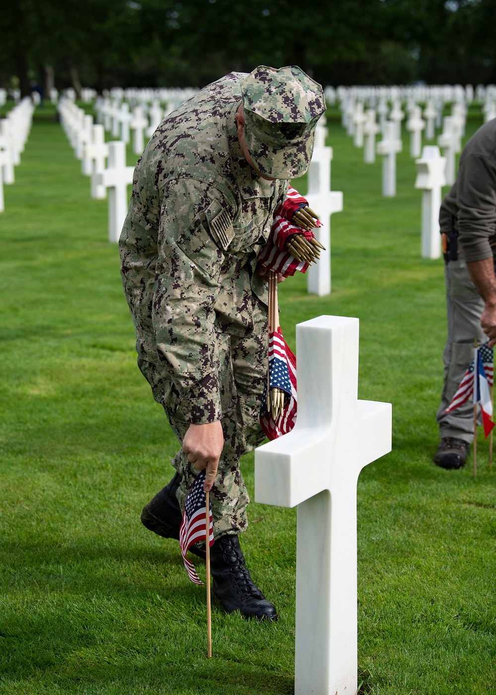 Sailor plants flags on WWII service member's graves commemorating D-Day's 75th anniversary.