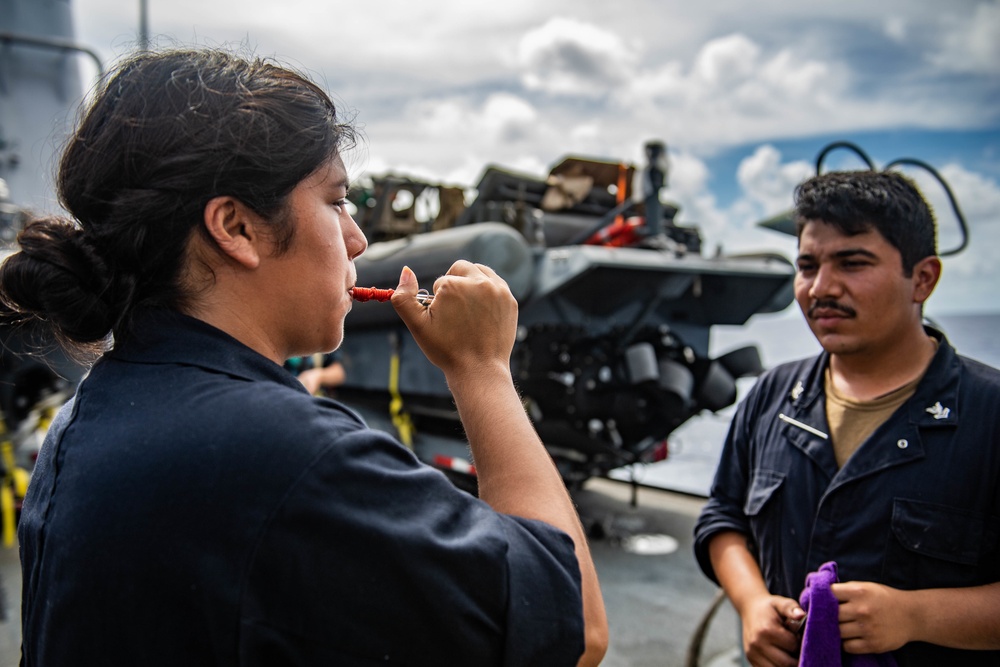 Sailor Aboard USS Harpers Ferry Practices Boatswain's Mate Pipe