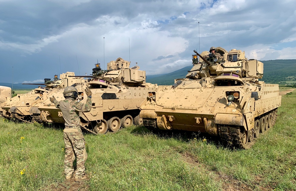 Soldier ground guides Bradley Fighting Vehicle during Saber Strike 19