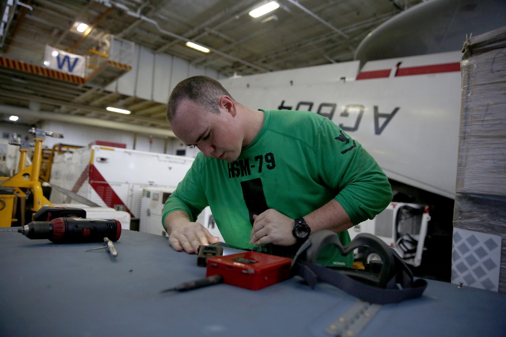 Sailors replace rotor blade on helicopter