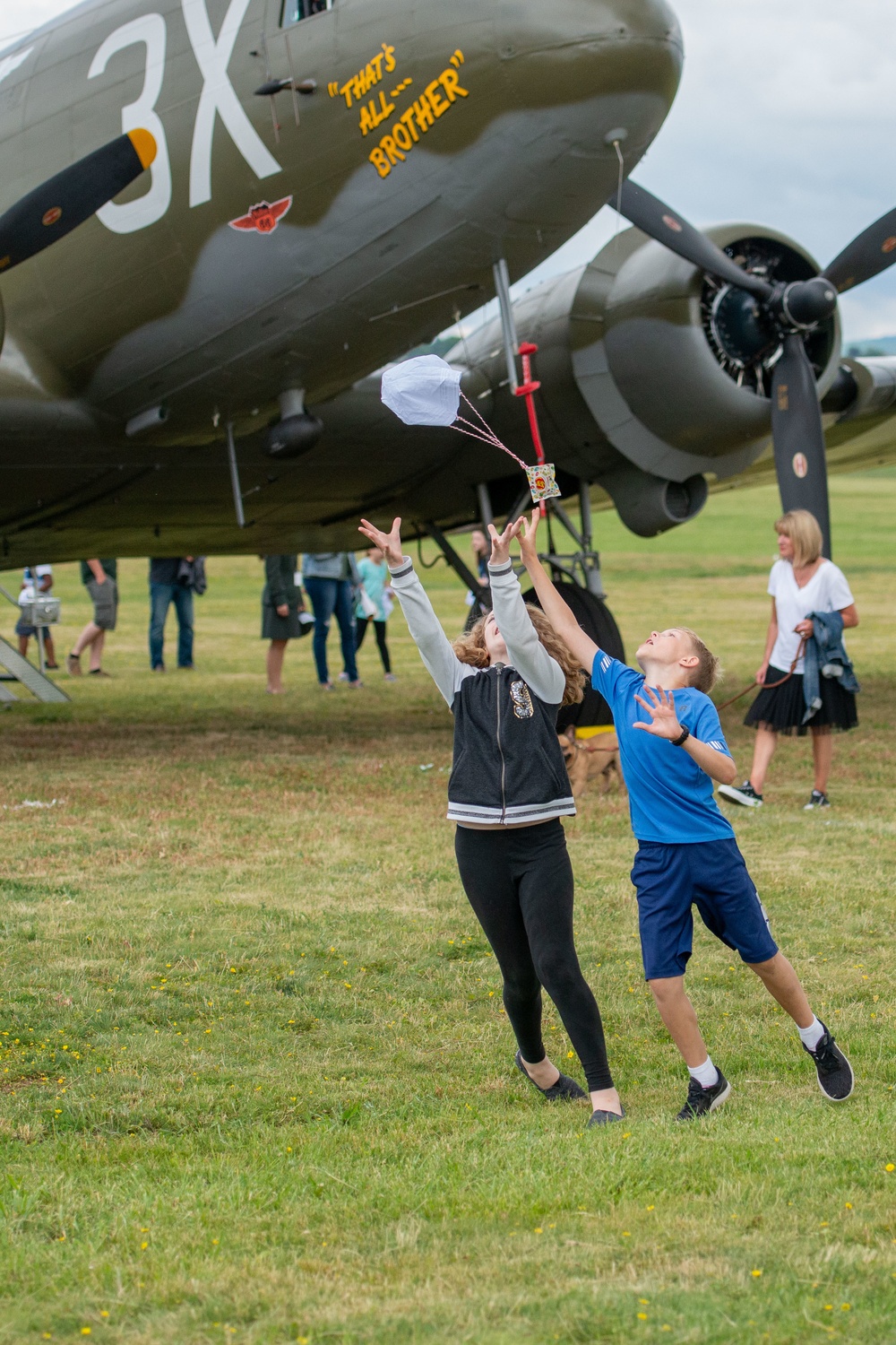 Children play with a &quot;Candy Parachute&quot; in front of a Dakota DC3 Aircraft