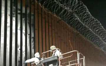 U.S. Soldiers apply paint to border wall