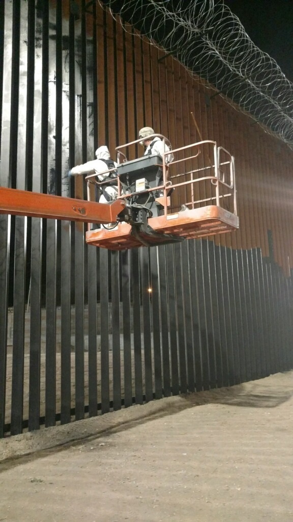 U.S. Soldiers apply paint to border wall